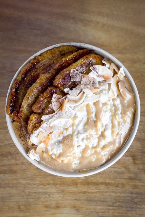 Millet porridge with caramelised bananas, roasted coconut chips, cinnamon, and almond butter