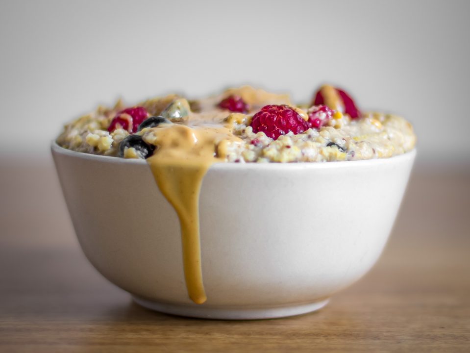 Millet Porridge with fresh raspberries and blueberries, topped with almond butter
