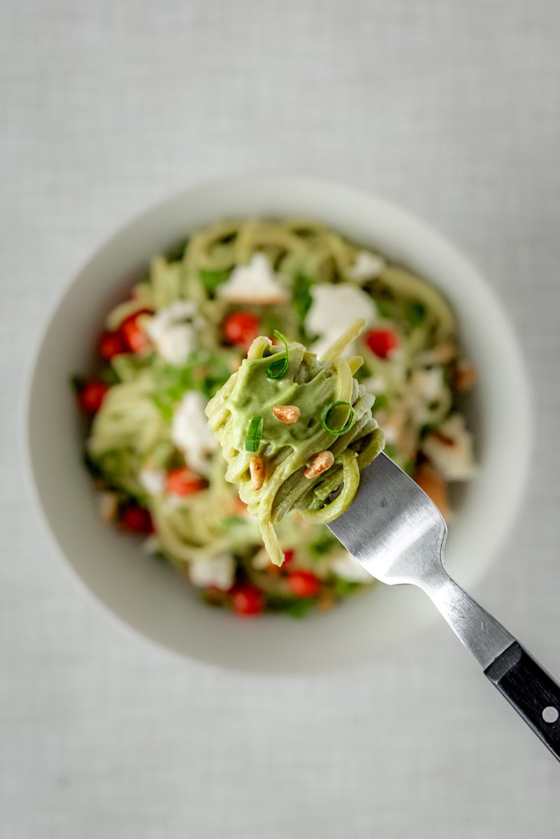 Close up of creamy vegan avocado pasta on a fork