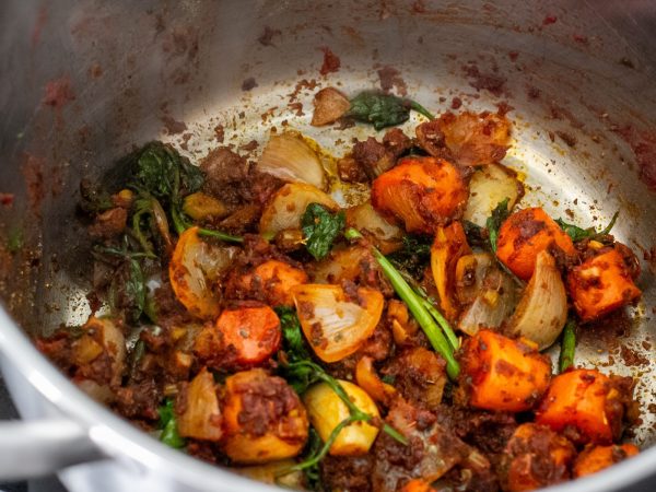 Preparation for a Turkish red lentil soup: A pot with veggies, and spices.