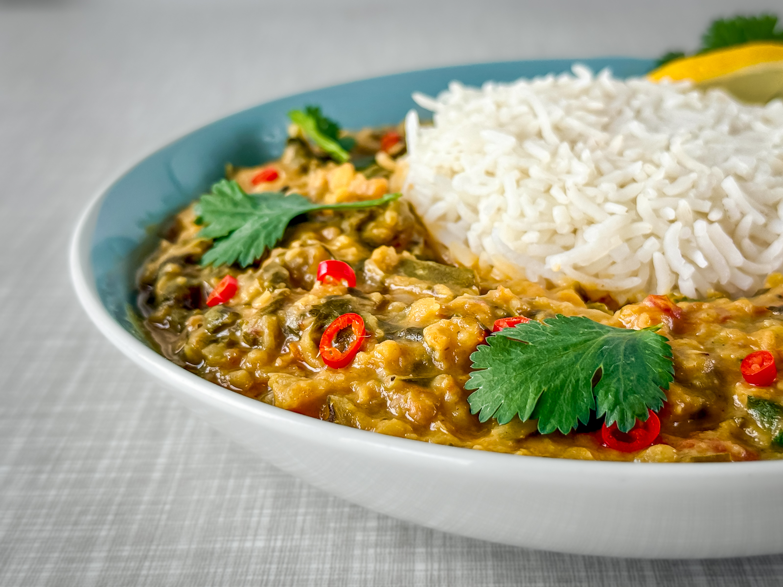 A close-up of a plate featuring a creamy Swiss chard and lentil curry served with basmati rice. Photographed from a diagonal front angle.
