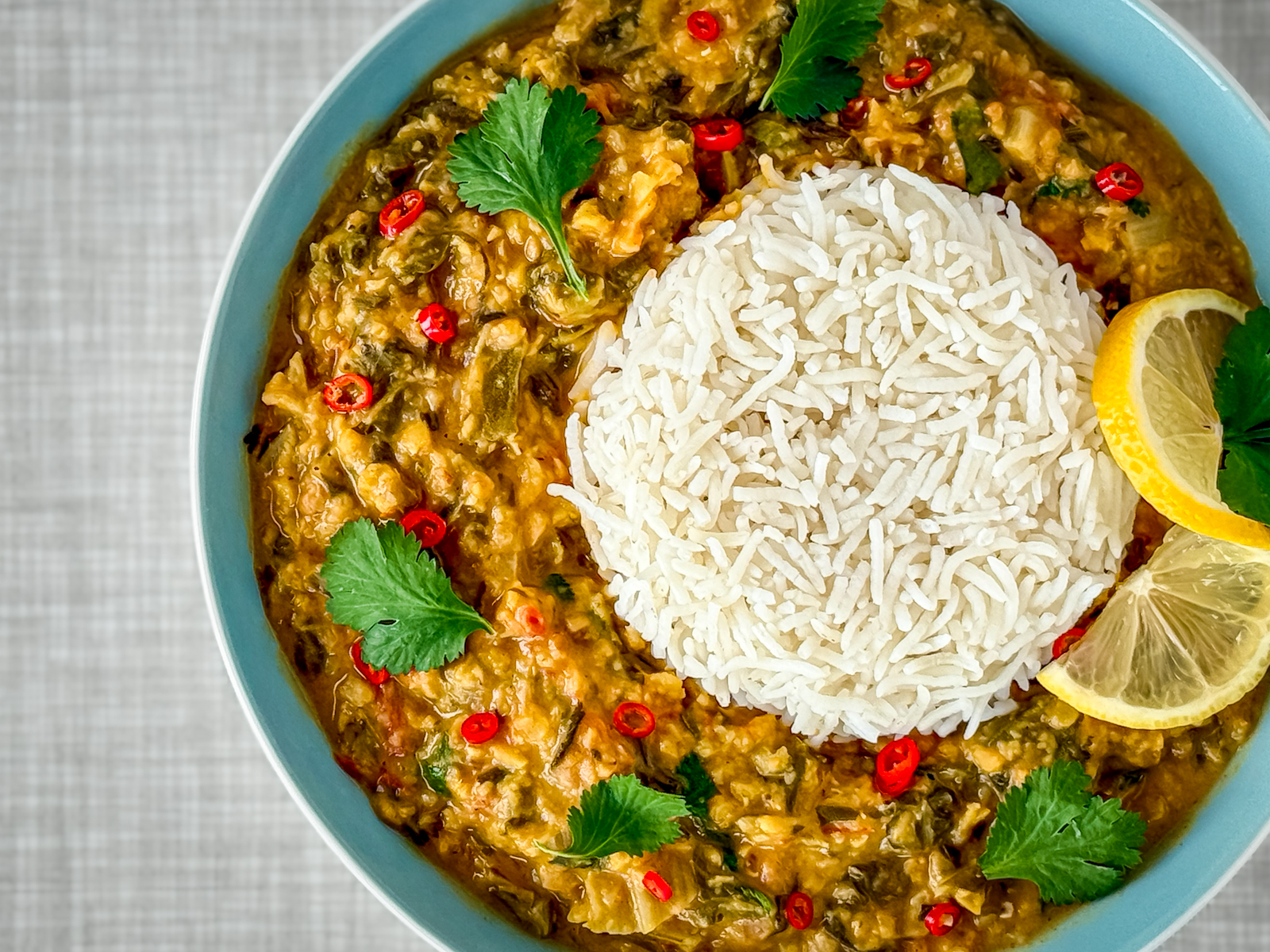 A close-up of a turquoise plate with creamy Swiss chard and lentil curry and basmati rice, photographed from above.