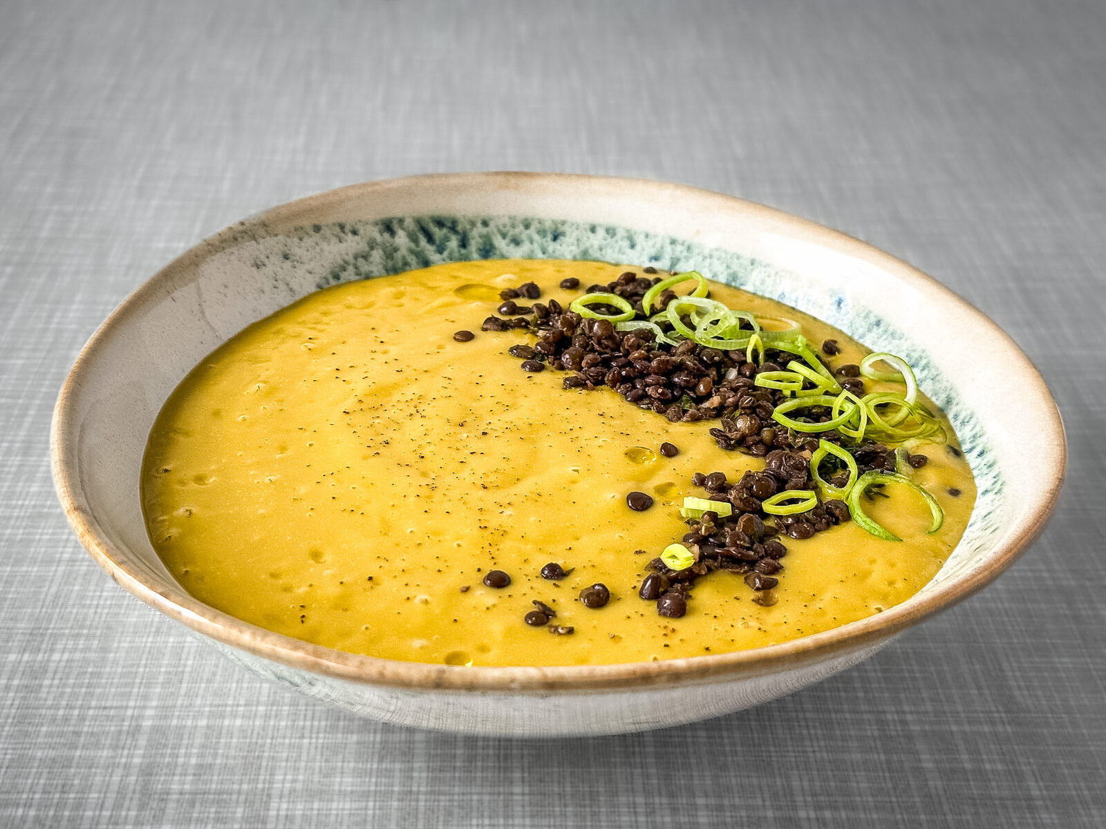Kartoffel Lauch Suppe mit Belugalinsen und Lauchringen von schräg vorne fotografiert