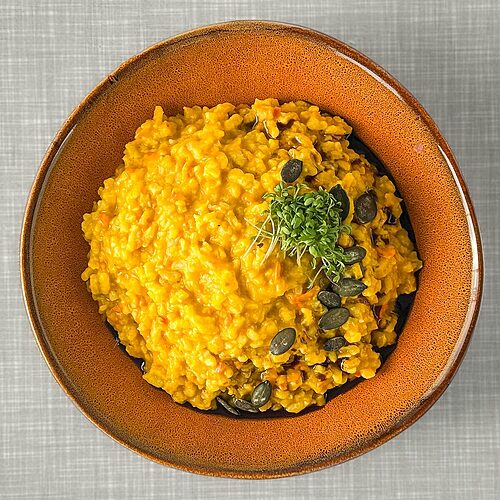 Cremiges Kürbisrisotto mit Kürbiskernöl, Kürbiskernen und Kresse verfeinert.